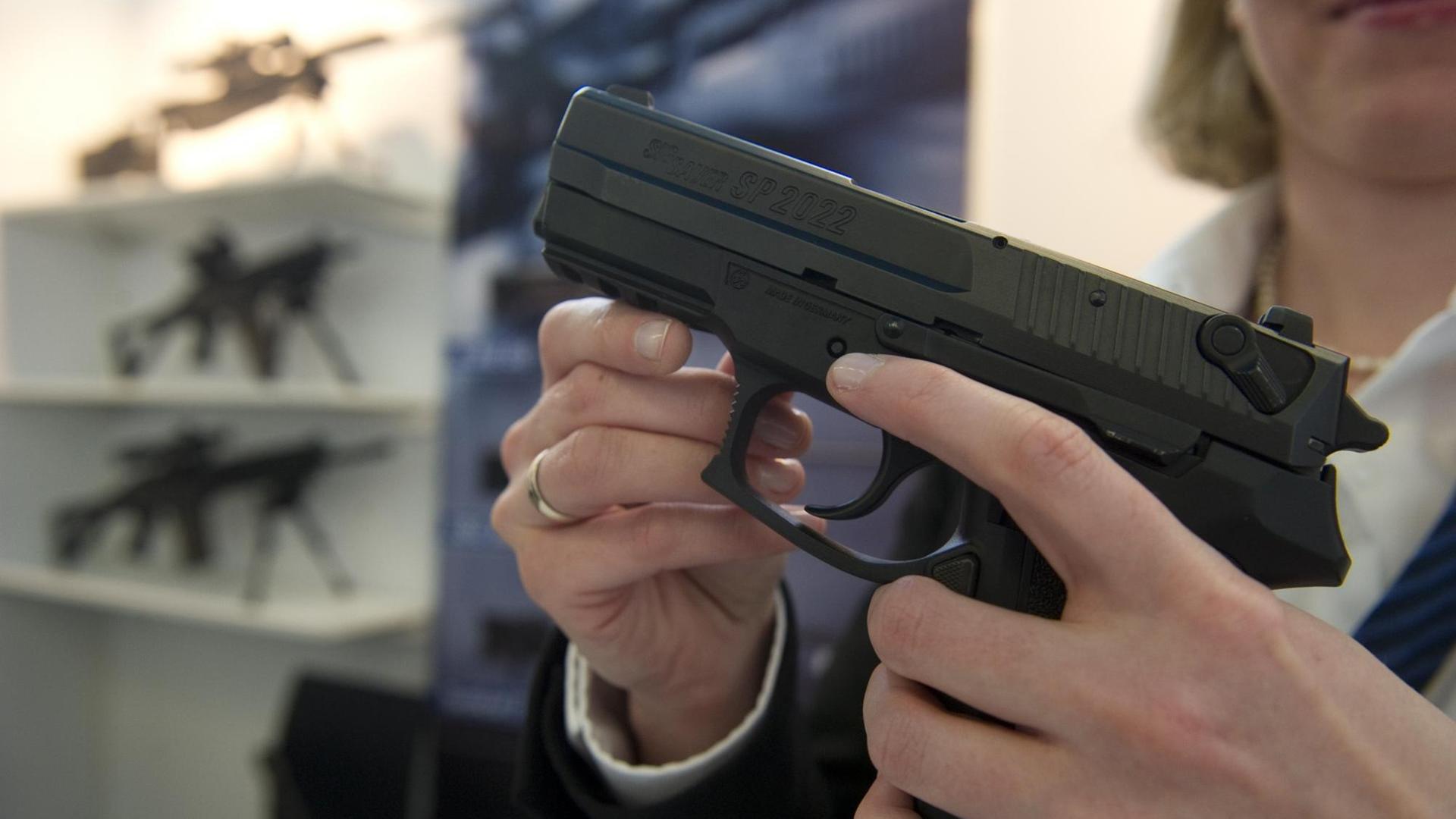 Eine Frau hält eine Sig-Sauer-Pistole vom Typ SP2022 in den Händen. Eine Frau hält eine Sig-Sauer-Pistole vom Typ SP2022 in den Händen.