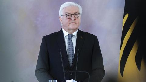 Bundespräsident Frank-Walter Steinmeier steht neben einer deutschen Flagge im Schloss Bellevue.