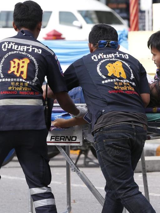 Rettungssanitäter transportieren eine verletzte Person nach einem Anschlag in Hua Hin zu einem Krankenwagen.
