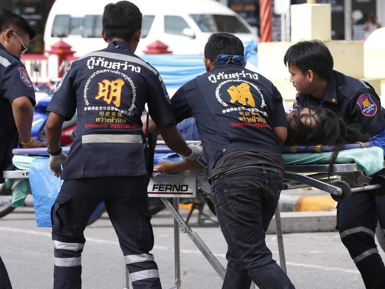 Rettungssanitäter transportieren eine verletzte Person nach einem Anschlag in Hua Hin zu einem Krankenwagen.