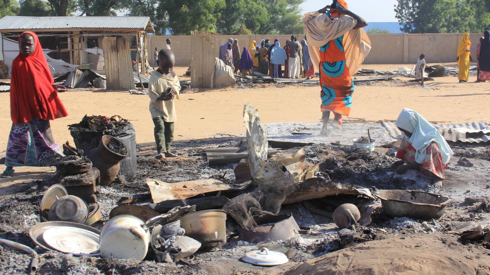 Nigeria: Ein Kind sucht nach einem Boko-Haram-Angriff nach Verwertbarem in einer niedergebrannte Hütte.