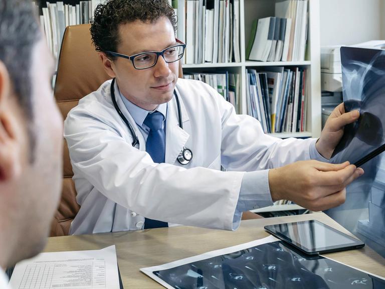 Ein Arzt erklärt seinem Patienten ein Röntgenbild.