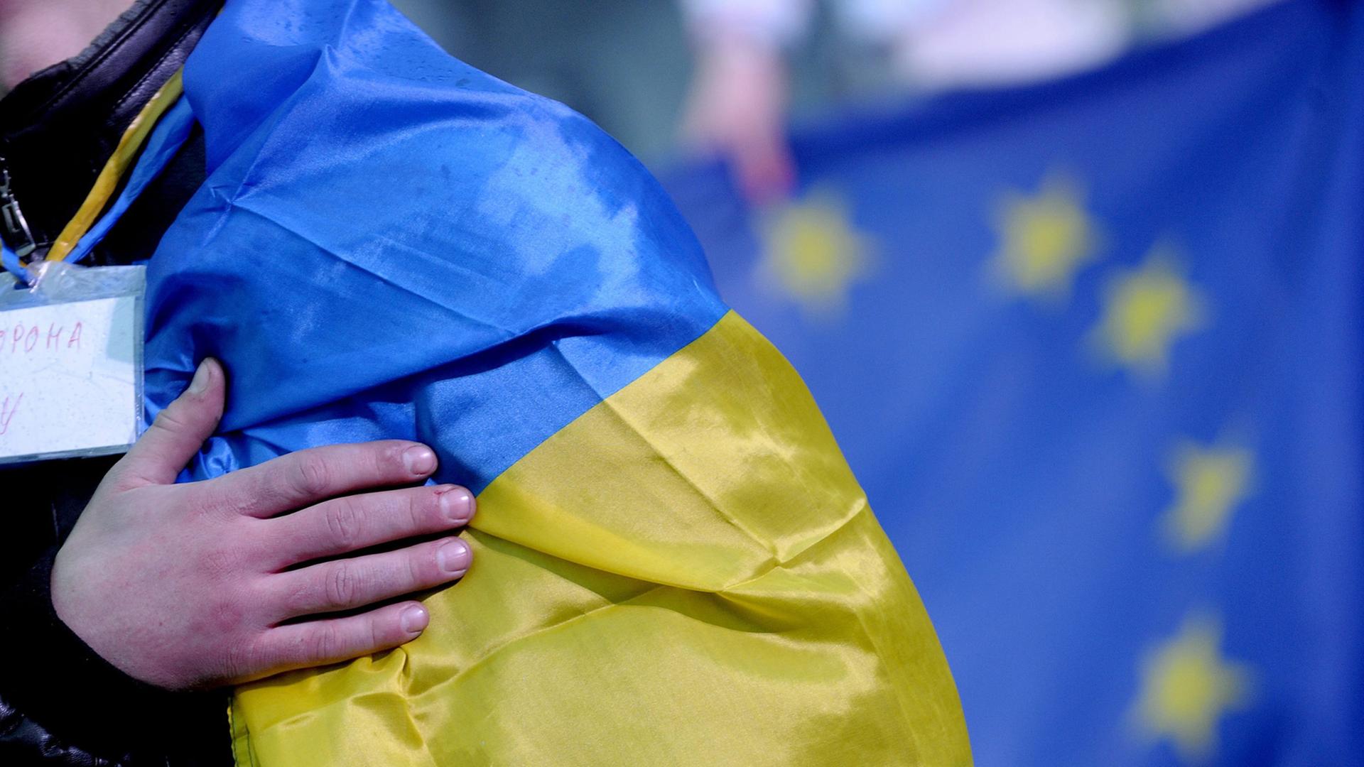 Ein Demonstrant mit den Farben der Ukraine vor einer Flagge der EU
