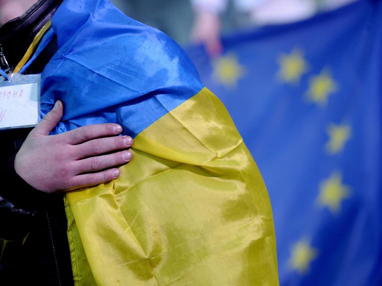 Ein Demonstrant mit den Farben der Ukraine vor einer Flagge der EU
