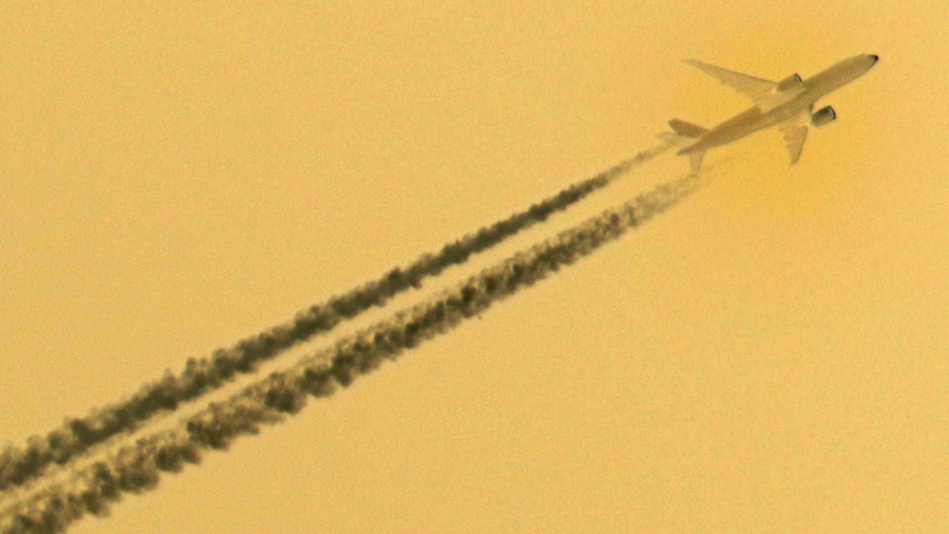 Invertierung eines Bildes, dass ein Flugzeug mit Kondensstreifen vor blauem Himmel zeigt.