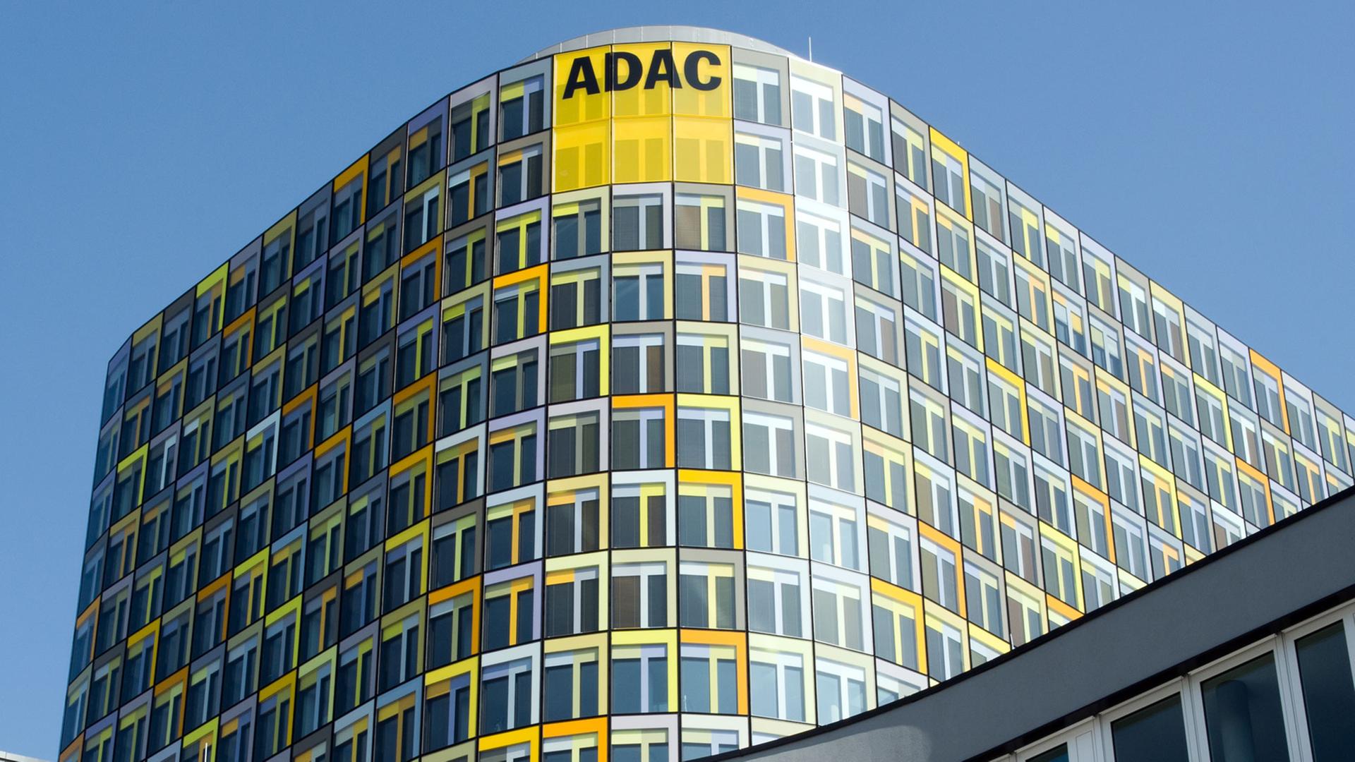 Blick auf die gelb-schwarze Fassade des Gebäudes mit einer runden Ecke unter blauem Himmel. 