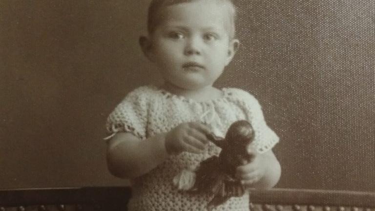 Schwarzweißfoto eines kleinen Mädchen, das eine schwarze Puppe in Händen hält. Schwarzweißfoto eines kleinen Mädchen, das eine schwarze Puppe in Händen hält.