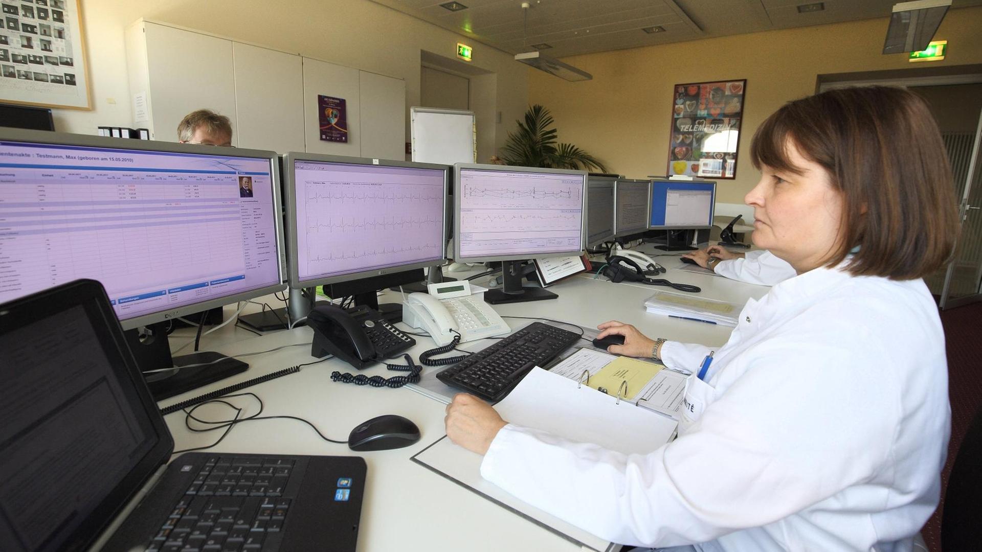 Eine Ärztin sitzt am Rechner und überprüft Daten eines Patienten.