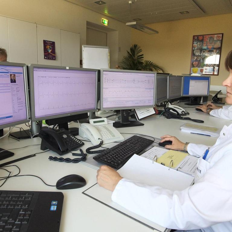 Eine Ärztin sitzt am Rechner und überprüft Daten eines Patienten.