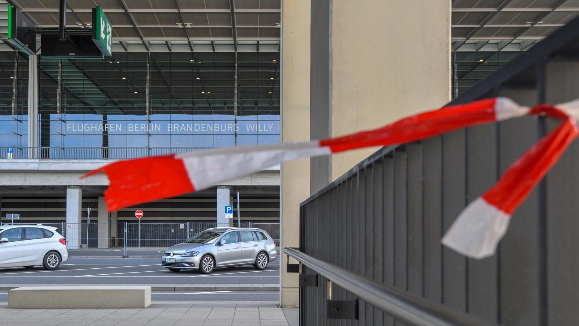 Der Rest eines Absperrbandes flattert im Wind an einem Geländer vor dem Terminal des Hauptstadtflughafens Berlin Brandenburg Willy Brandt.