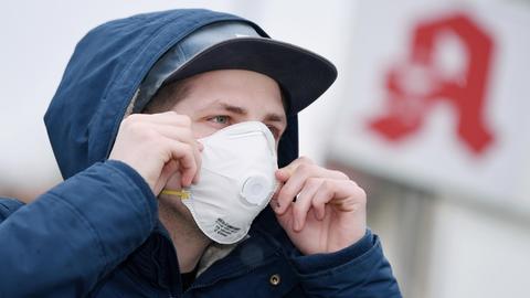 Ein Mann mit einer Schutzmaske vor einer Apotheke, Schutzmasken sind fast ausverkauft.