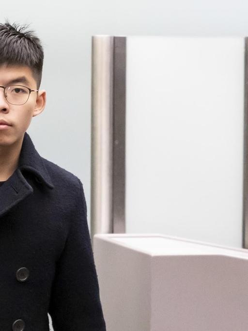 Joshua Wong, Demokratie-Aktivist der Proteste in Hongkong, in dunkler Jacke und mit einem Rucksack über der Schulter, kommt bei seiner Ankunft am Flughafen Tegel aus dem Sicherheitsbereich.