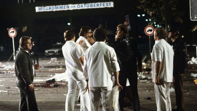 Mitarbeiter der Spurensicherung stehen nach dem Bombenanschlag auf dem Münchener Oktoberfest am 26.09.1980 in der Dunkelheit vor einem Bild der Verwüstung.