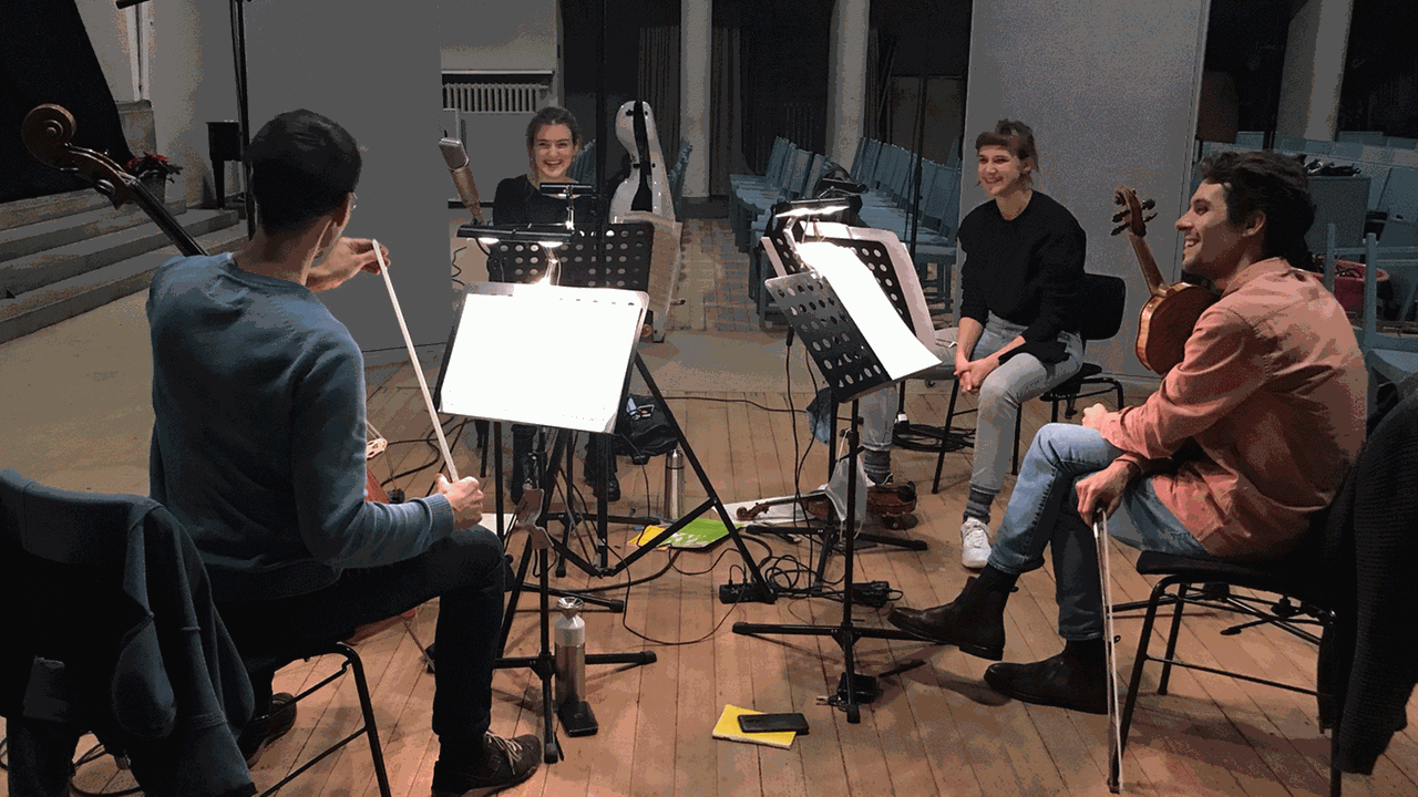 Vier Musiker sitzen mit ihren Streichinstrumenten im Kreis in einer Kirche