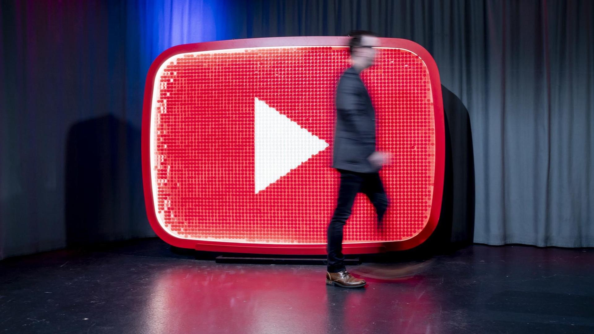 Ein Mann läuft beim YouTube-Jahresrückblick 2018 im YouTube Space Berlin vor einem YouTube-Logo.