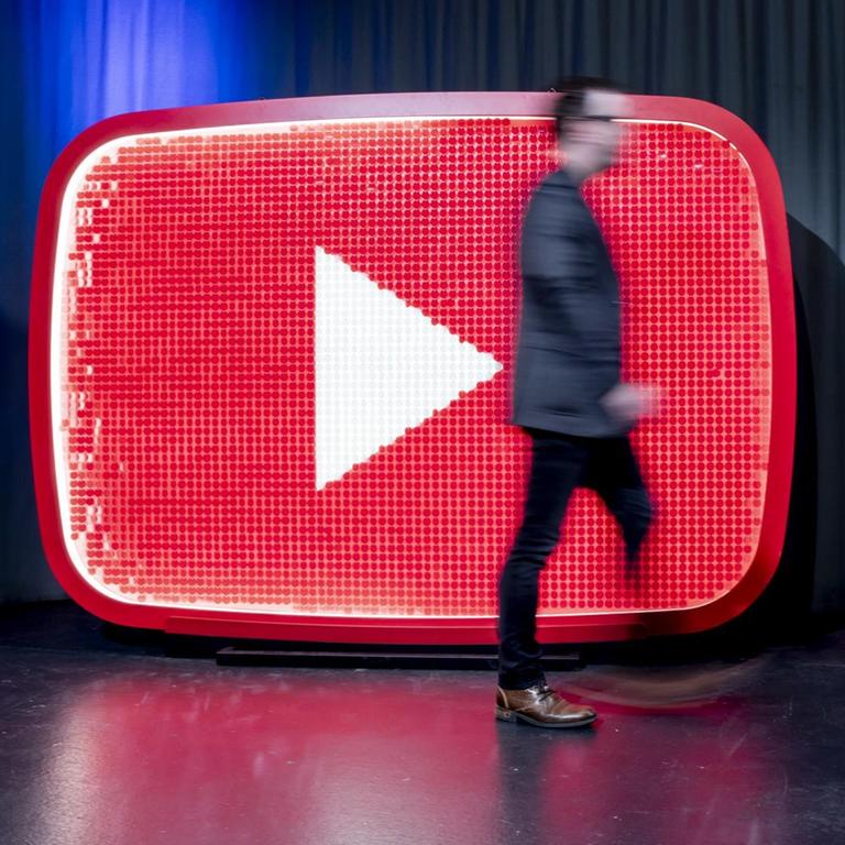 Ein Mann läuft beim YouTube-Jahresrückblick 2018 im YouTube Space Berlin vor einem YouTube-Logo.