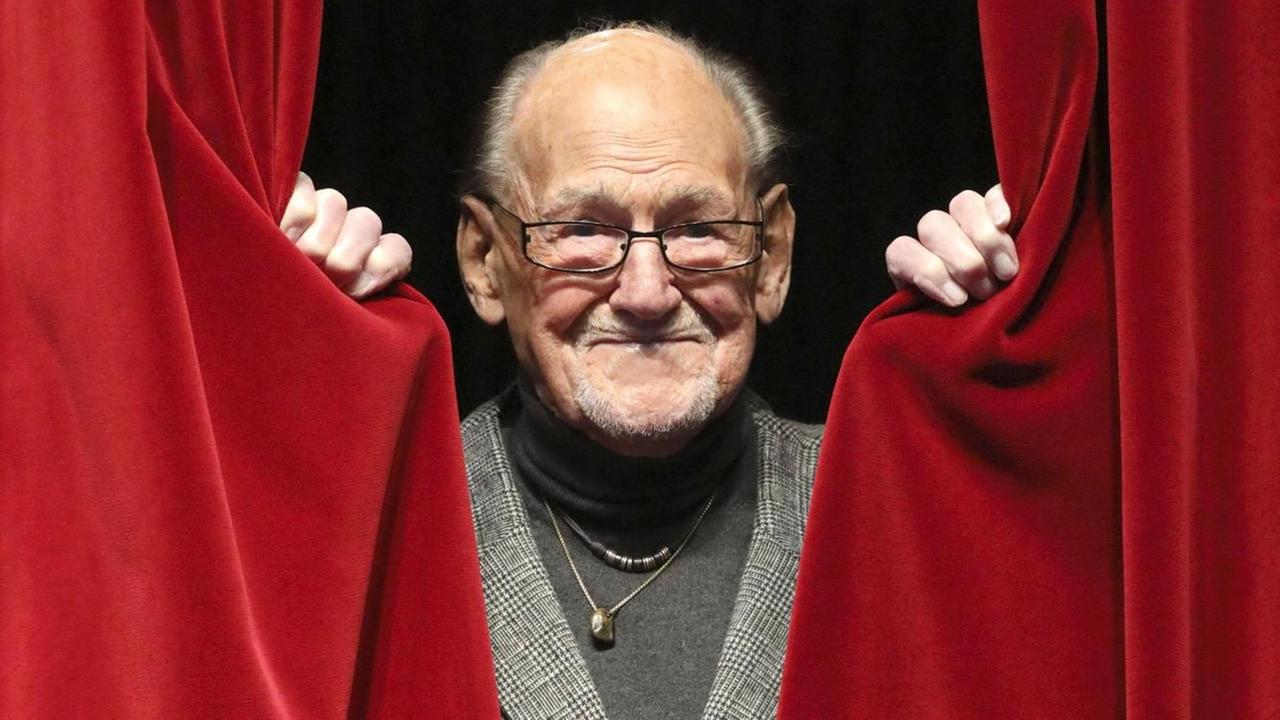 Herbert Köfer erscheint in der Mitte eines geöffneten roten Vorhangs