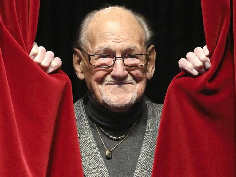 Herbert Köfer erscheint in der Mitte eines geöffneten roten Vorhangs