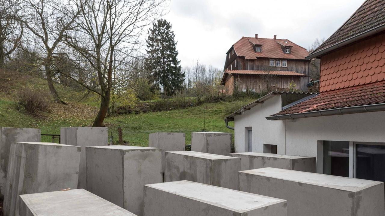 Neben einem Einfamilienhaus im ländlichen Raum sind dem Holocaust-Mahnmal in Berlin nachempfundene Betonstelen aufgebaut.
