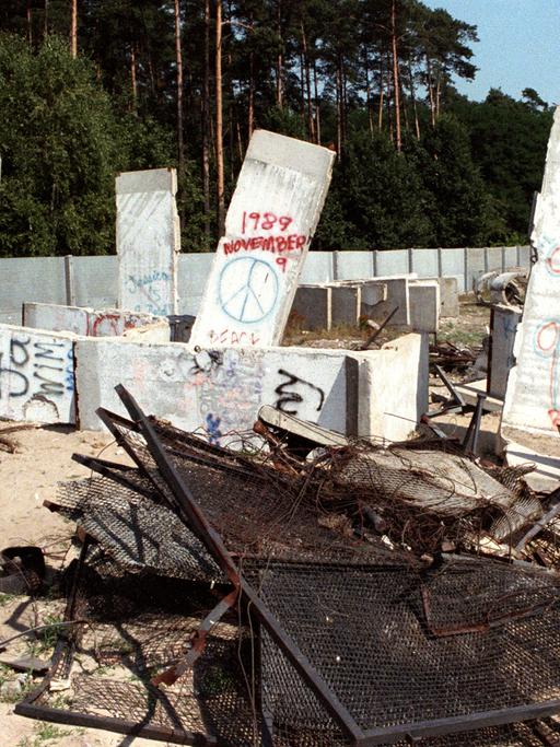 Trümmer der Geschichte - Teile der Betonmauer, Stacheldraht, Gitterzaun und Betonreste der Berliner Mauer liegen im Ortsteil Steinstücken bei Potsdam auf einem Gelände, aufgenommen im August 1990. 