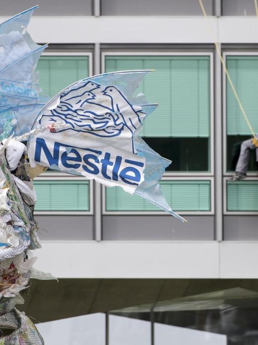 Greenpeace-Aktivisten bringen dem Lebensmittel- und Getränkegiganten Nestlé ein riesiges Monster aus Plastik zurück, das Greenpeace auf See und an den Stränden vor dem Hauptsitz von Nestle in Vevey, Schweiz geborgen hat.