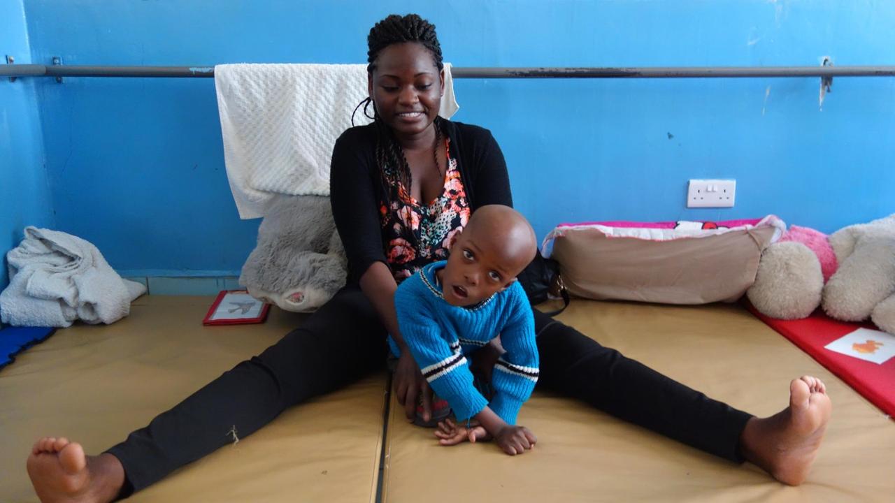 Zentrum für behinderte Kinder im kenianischen Mukuru. Auch der kleine Jeremy hat Hirnschäden infolge Sauerstoffmangels durch zu lange Wehen erlitten. Er sitzt auf dem Bett mit Betreuerin.