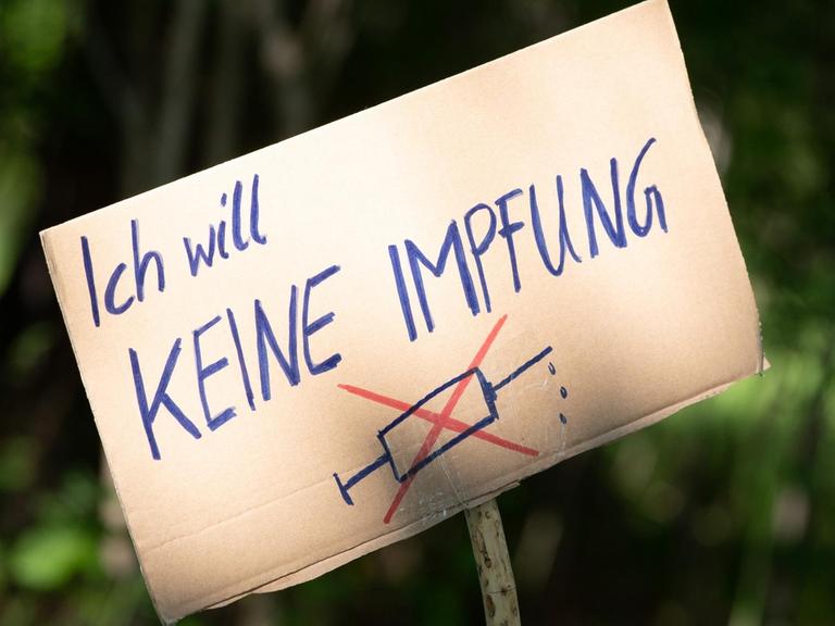 Ein Schild mit der Aufschrift "Ich will keine Impfung" wird an einem Stock hochgehalten.