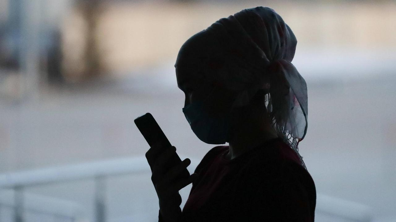 Kirgisin mit Mundschutz und Smartphone