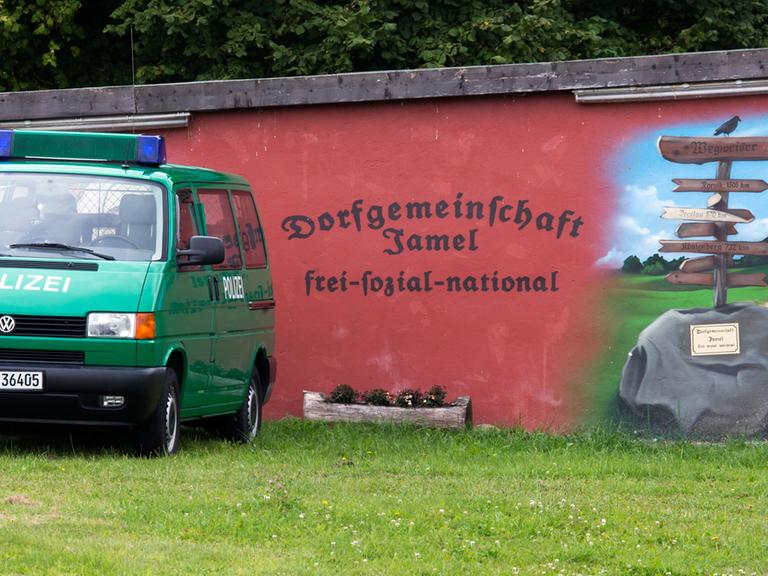 Polizisten stehen am 30.08.2014 am Rande des Rockfestivals "Jamel rockt den Förster" in Jamel von einem von rechtsradikalen Dorfbewohnern bemalten Haus.