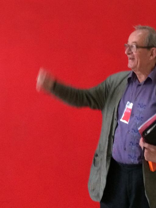 Kasper König gestikuliert vor einem roten Hintergrund
