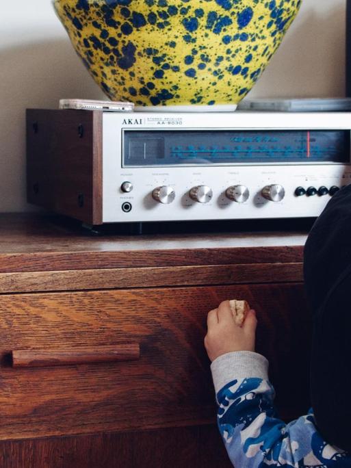 Ein Kleinkind dreht am Knopf eines alten Radios.