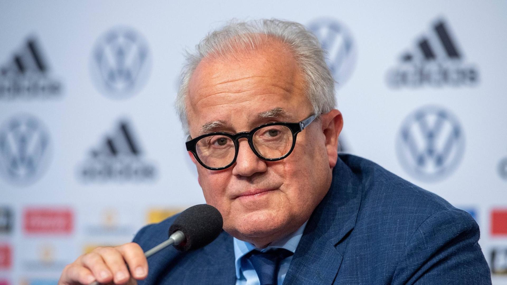 Der ehemalige Präsident des Deutschen Fußball-Bundes, Fritz Keller, sitzt auf einer Pressekonferenz und hat ein Mikrofon in der Hand. 