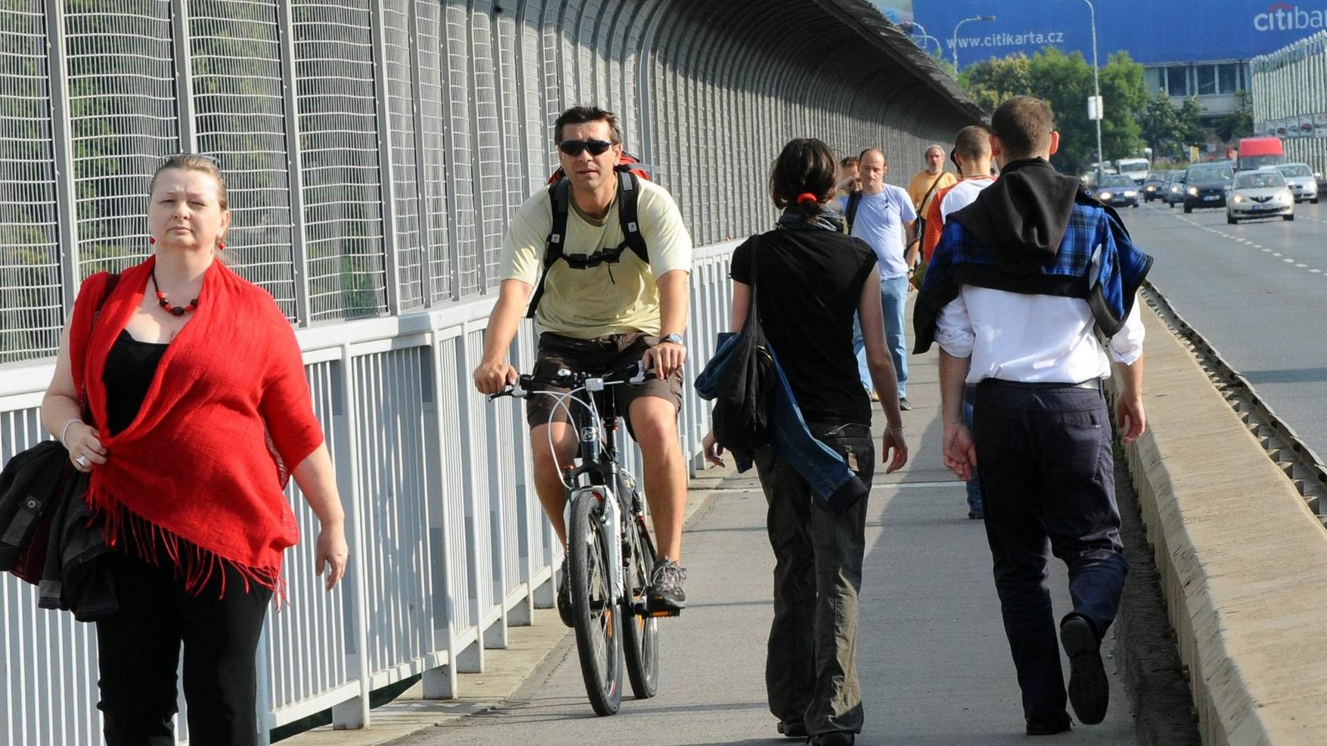 Radfahrer fährt neben Fußgängern