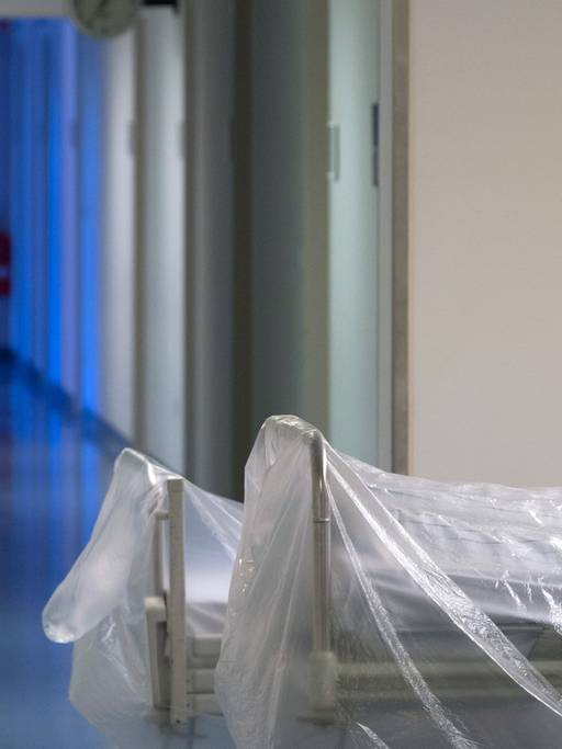Zwei mit durchsichtiger Folie überzogene Krankenhausbetten stehen auf einem Krankenhausflur.