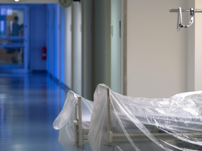 Zwei mit durchsichtiger Folie überzogene Krankenhausbetten stehen auf einem Krankenhausflur.