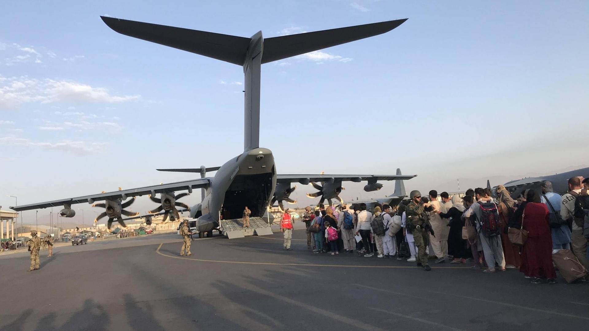 Menschen stehen Schlange, um ein deutsches Militärflugzeug zu besteigen und Kabul am Flughafen von Kabul zu verlassen.