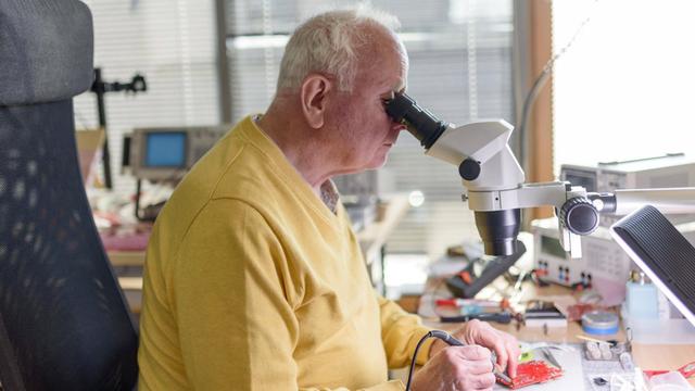 Ein älterer Mann arbeitet an einem Mikroskop.