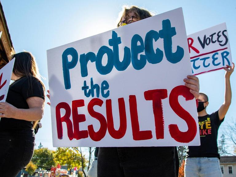 "Protect the results" steht auf einem Plakat von Demonstranten.
