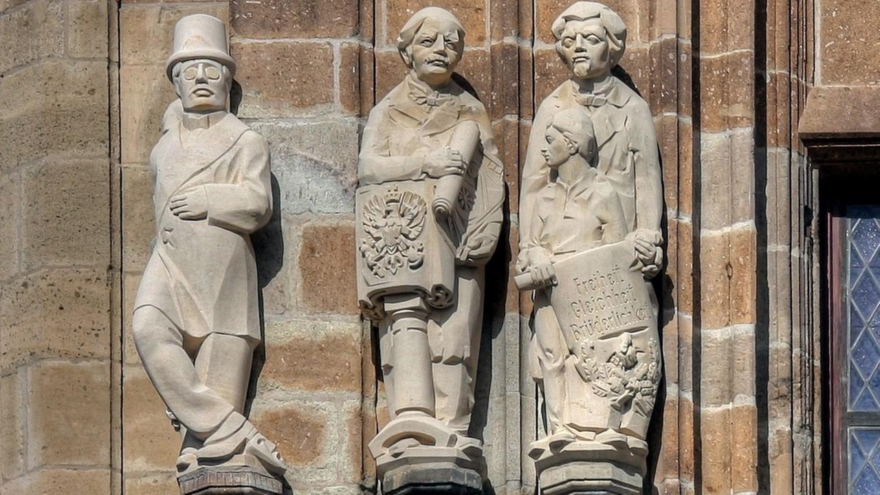 Jaques Offenbachs als Steinfigurine an einer historischen Steinfassade in einer Reihe anderer historischer Figuren