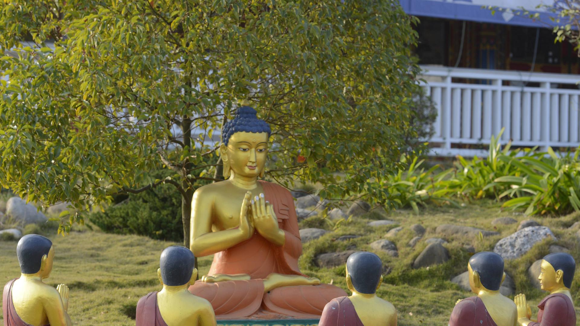 Denkmal vom sitzenden Buddha mit seinen Juengern im Tempel Karma Kagyo Monastery im Heiligen Garten von Lumbini - dem Geburtsort von Siddhartha Gautama, den wir unter der Bezeichnung Buddha kennen.
