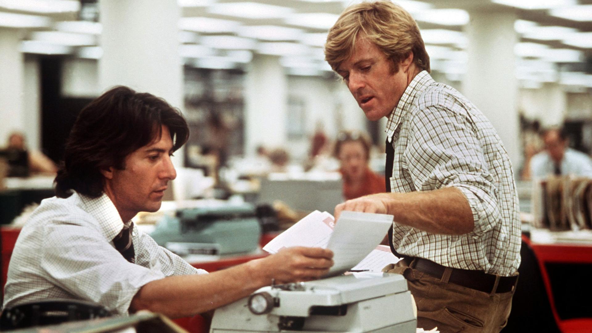 Filmszene aus "Die Unbestechlichen": Dustin Hoffman als Carl Bernstein an einer Schreibmaschine, Robert Redford als Bob Woodward sitzt auf der Schreibtischkante