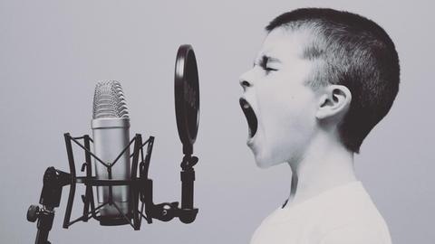 Ein Junge schreit in ein Mikrofon.