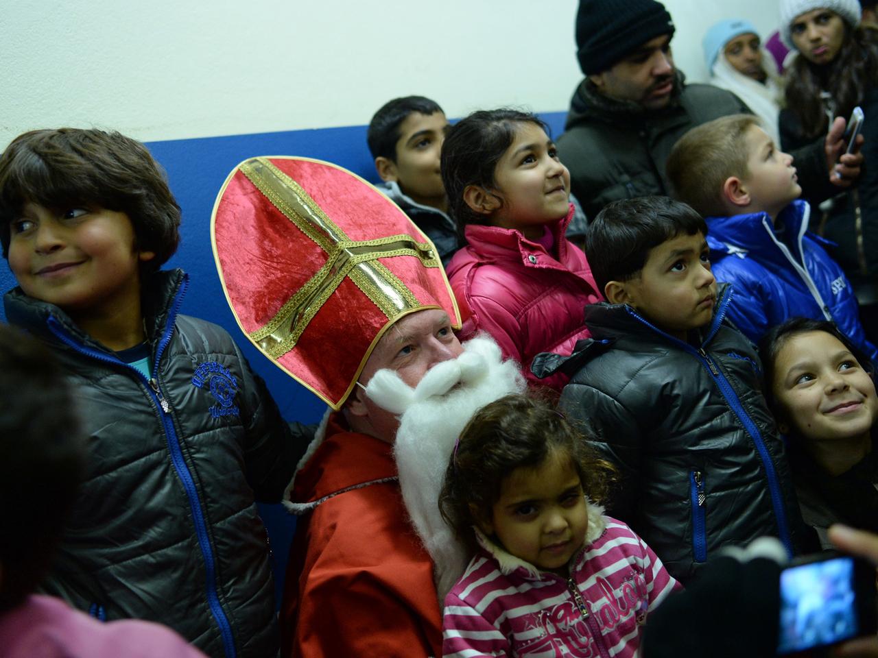 Ein Mann im Nikolauskostüm inmitten von Flüchtlingskindern