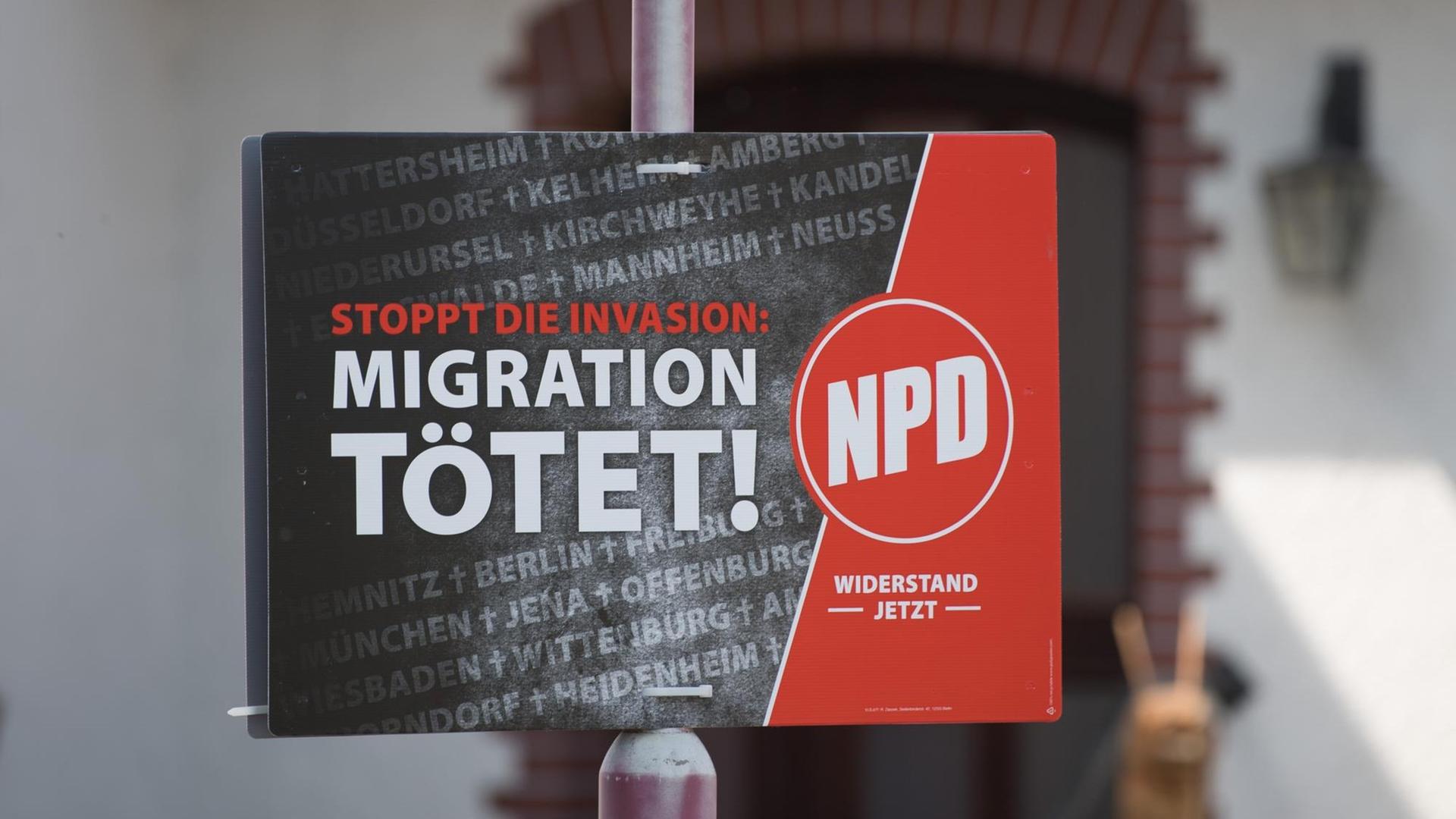 Ein Wahlplakat der rechtsextremen Nationaldemokratischen Partei Deutschlands (NPD) mit der Aufschrift "Migration Tötet" hängt an einem Lampenpfahl.