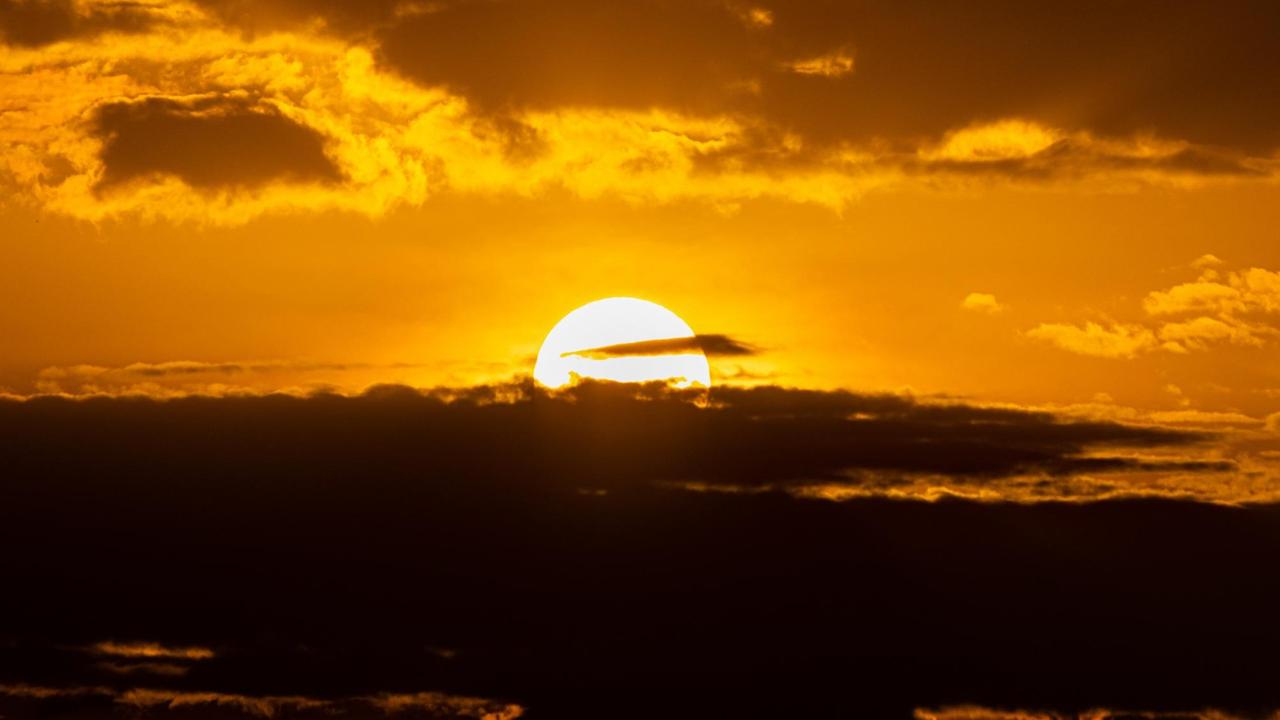Die Sonne bricht durch eine dunkle Wolkendecke.