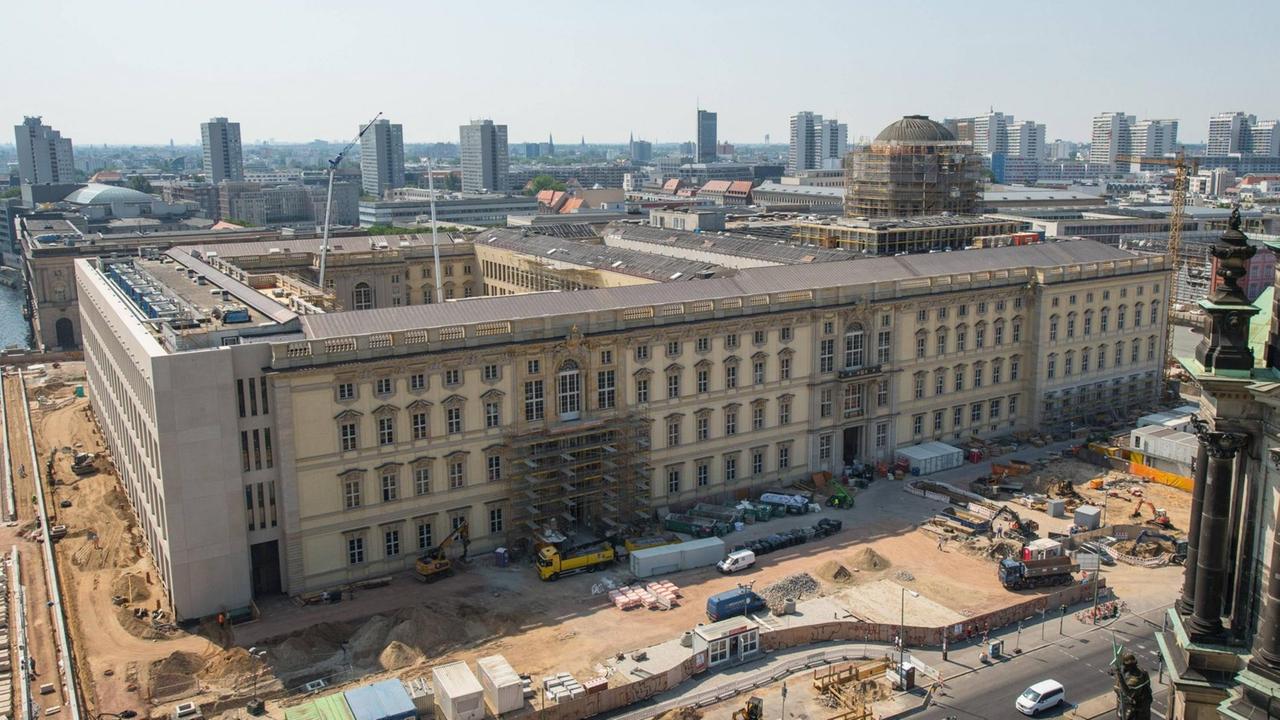 Die Baustelle des Berliner Humboldt Forums. Teile des Gebäudes sind noch mit Baugerüsten versehen. Kräne und Baumaschinen stehen herum.
