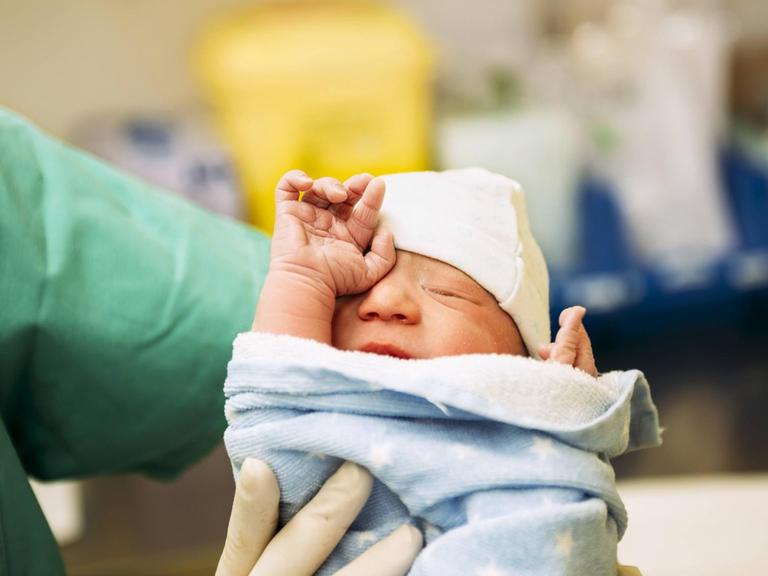 Ein neugeborenes Baby, in eine Decke gewickelt.(Symbolfoto)