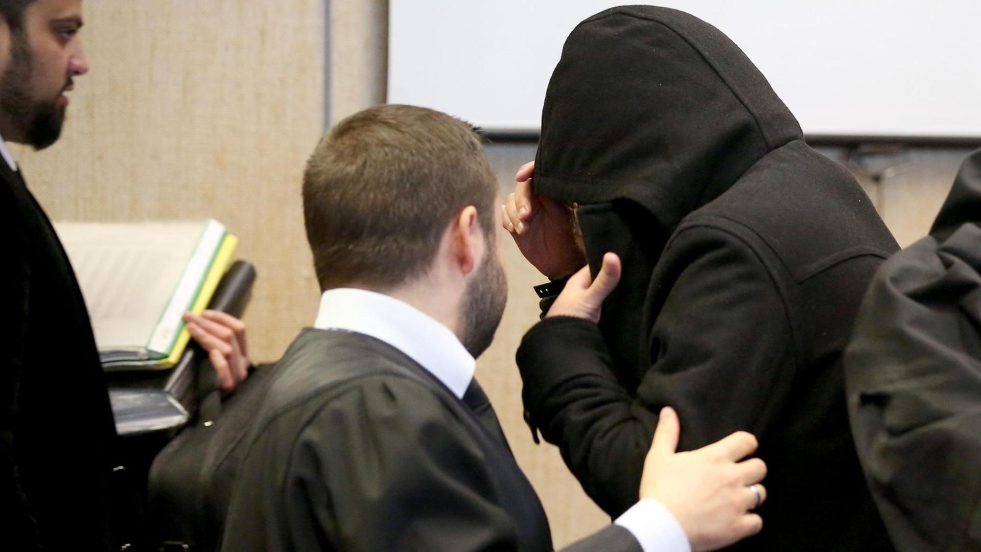 Ein Angeklagter steht mit Kapuze über dem Gesicht am 30.01.2017 in Köln (Nordrhein-Westfalen) im Landgericht zwischen seinen Anwälten.