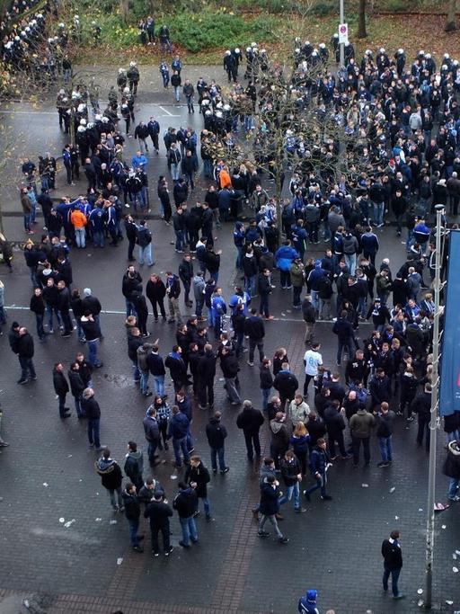 Schalkefans stehen durch Polizisten getrennt von den Dortmund-Fans vor dem Stadion. Luftaufnahme