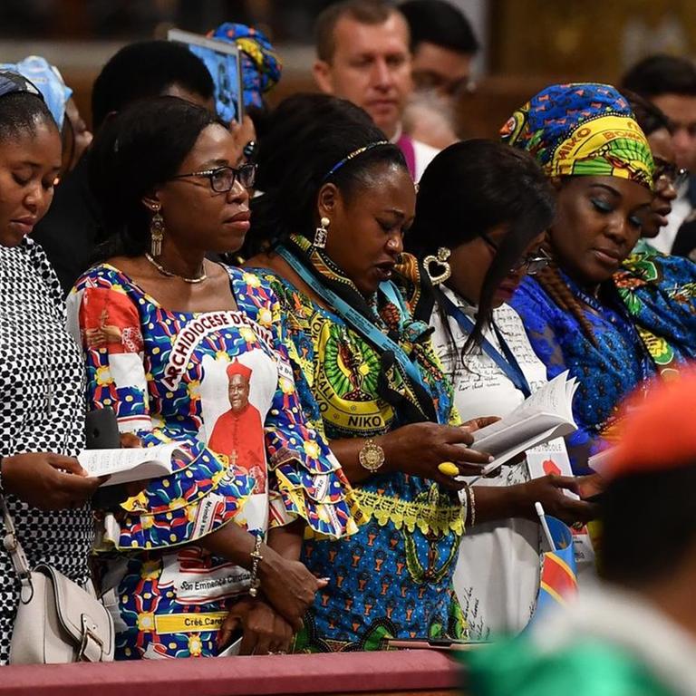 Frauen aus der Amazonas-Region stehen während der Messe in den Kirchenbänken. Daneben: Geistliche und Messdiener.